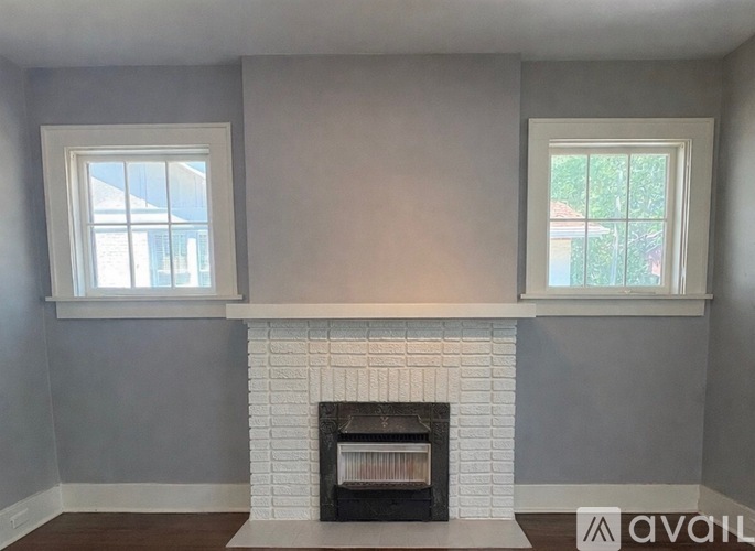 A room with a fireplace and two windows.