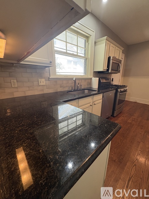 A kitchen with a black counter top and white cabinets.