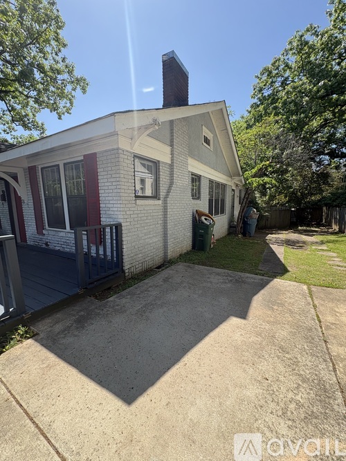 A house with a white brick exterior and a red door is for sale.