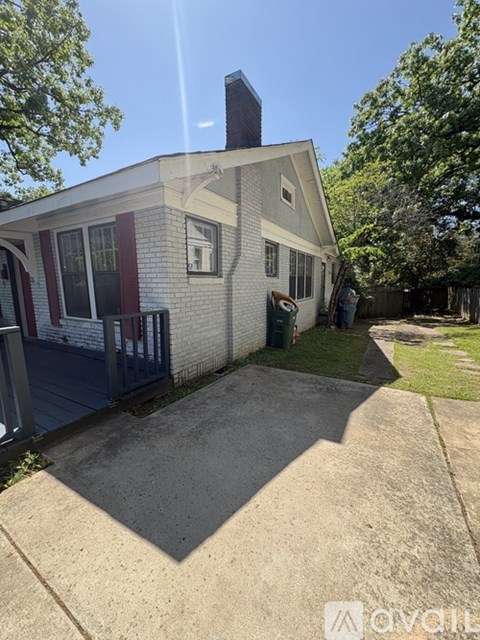 A house with a white brick exterior and a red door is for sale.