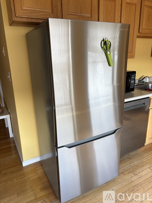 A silver refrigerator with a green magnet on it.