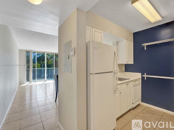 A kitchen area with a refrigerator, sink, and cabinets.