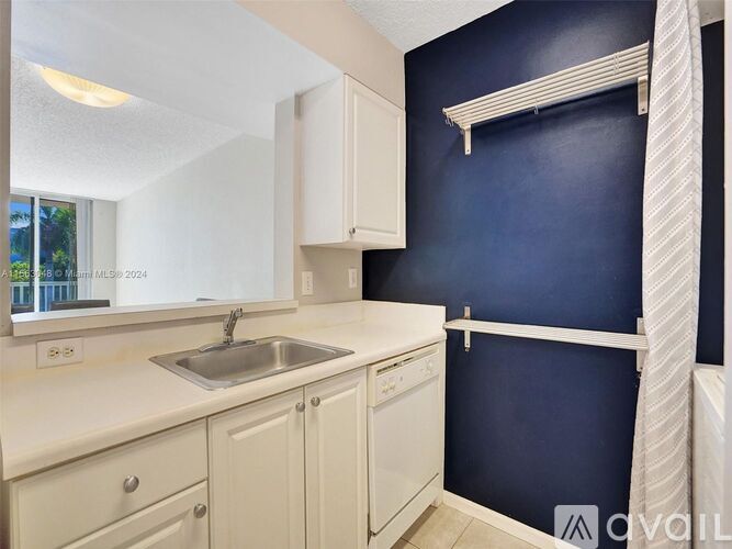 A kitchen with white cabinets and a blue wall.