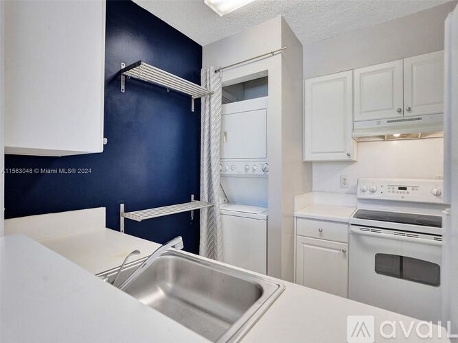 A kitchen with white appliances and a blue wall.