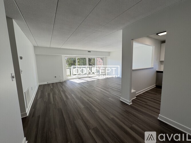 A spacious room with wooden flooring and white walls.