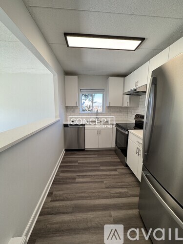 A kitchen with a refrigerator, cabinets, and a window.