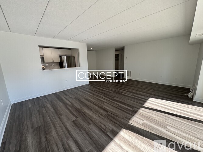 A spacious room with wooden flooring and a large window.