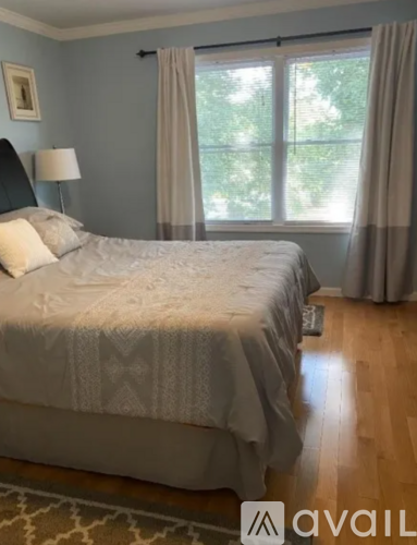 A bedroom with a large bed and a window with curtains.