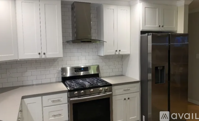 A kitchen with white cabinets and a stainless steel refrigerator.