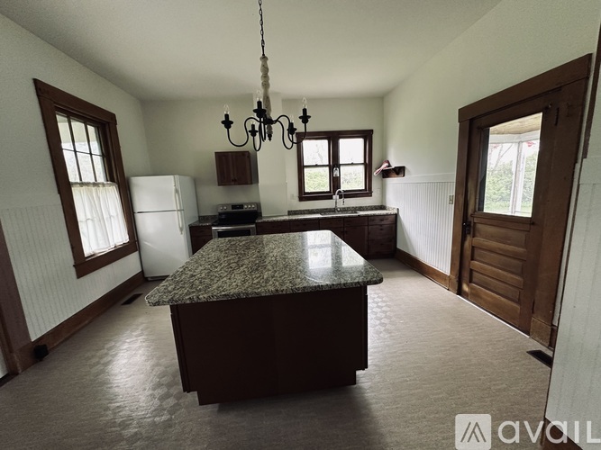 A kitchen with a granite countertop and a chandelier hanging from the ceiling.