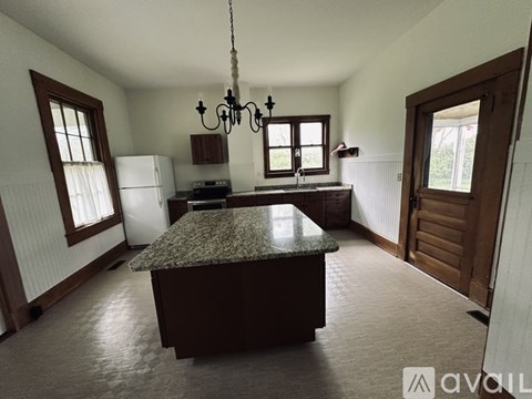 A kitchen with a granite countertop and a chandelier hanging from the ceiling.