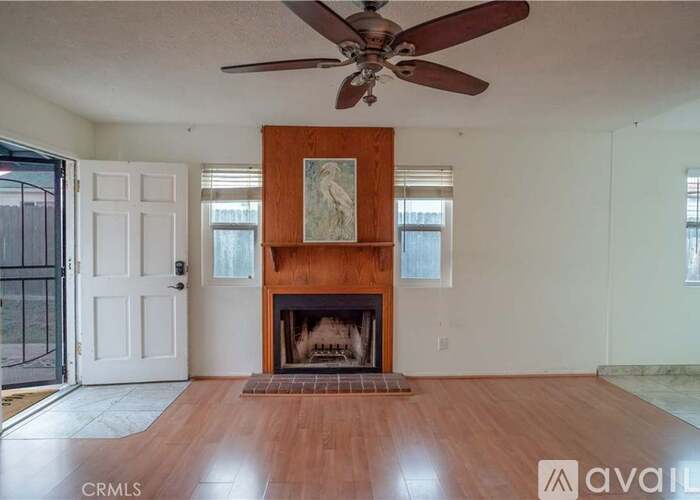 A living room with a fireplace and a ceiling fan.