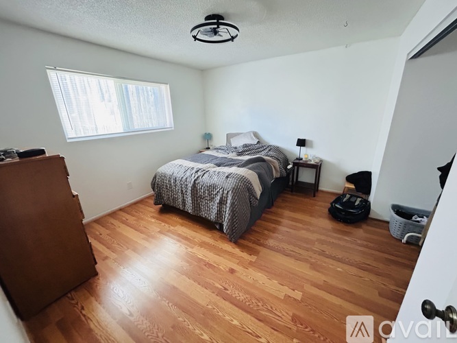 A bedroom with a bed, nightstand, and window.
