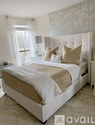 A bedroom with a large bed and a window with curtains.