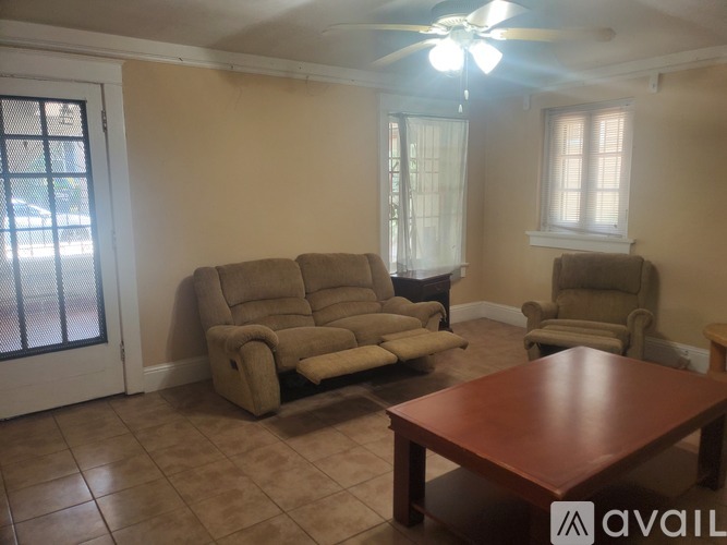 A living room with a brown sofa, a brown armchair, and a wooden table.