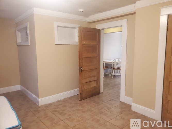 A room with a wooden door leading to a dining area.