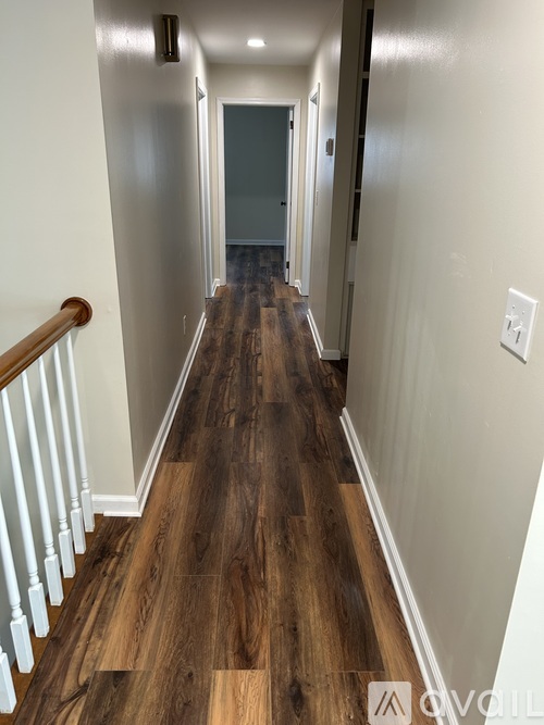 A hallway with wood floors and white walls.
