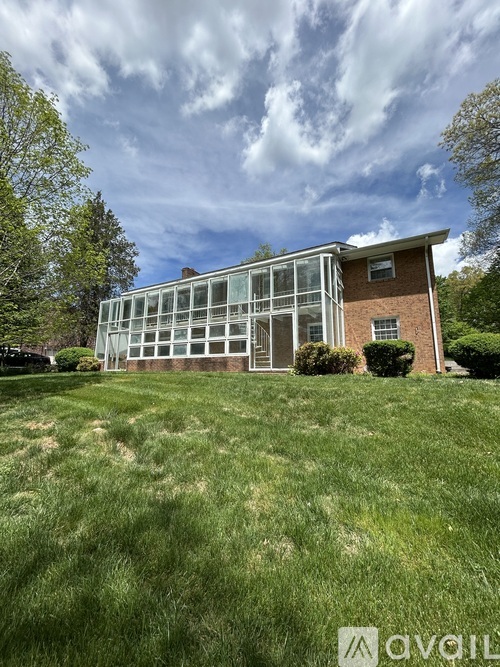A modern house with a large glass wall is surrounded by a grassy lawn.