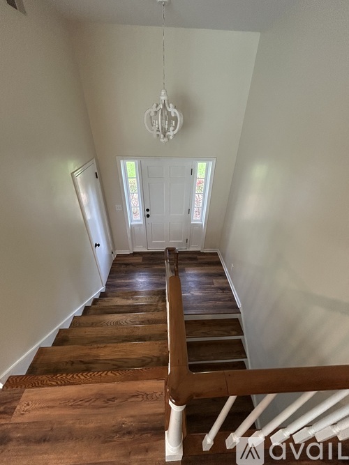 A wooden staircase with a chandelier hanging from the ceiling.