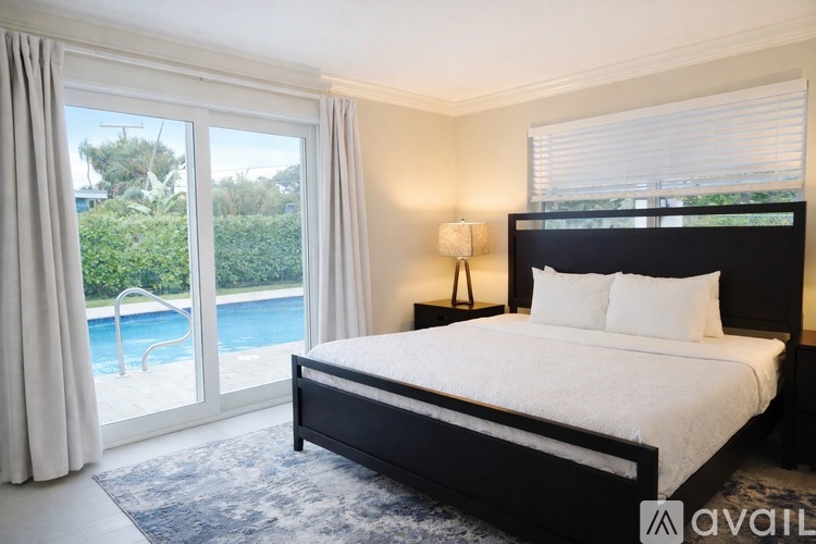 A bedroom with a large bed and a view of a pool through the window.