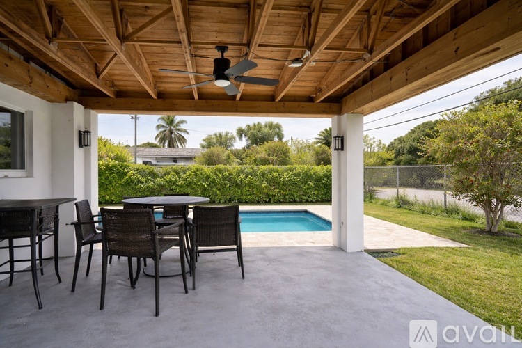 A patio with a table and chairs overlooking a pool.