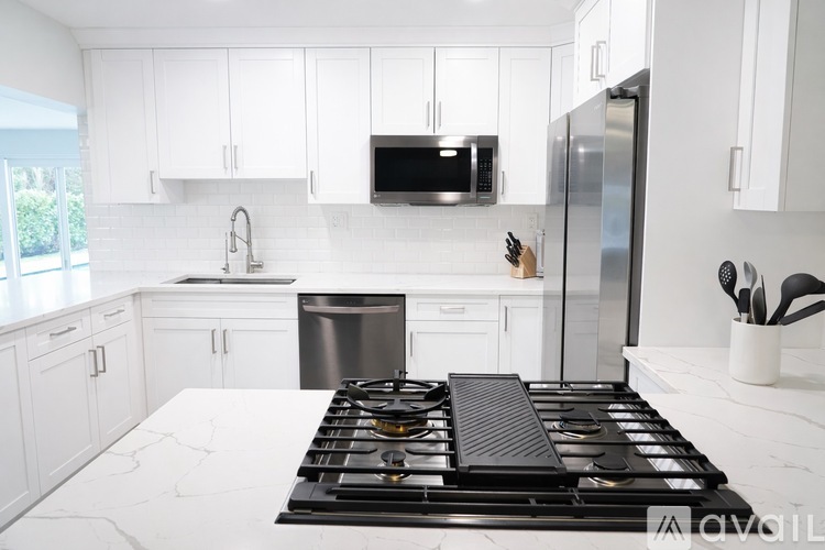 A modern kitchen with a stove top in the foreground.