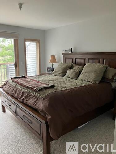 A bedroom with a large bed and a window with blinds.