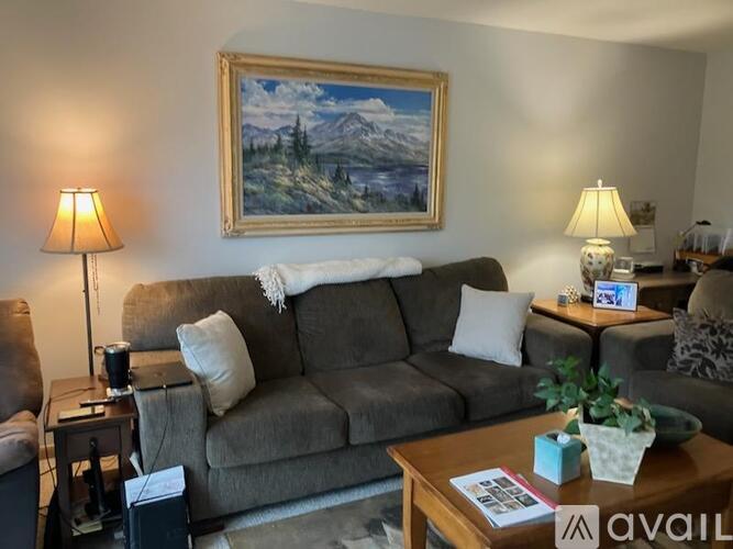A living room with a painting of a mountain landscape on the wall.