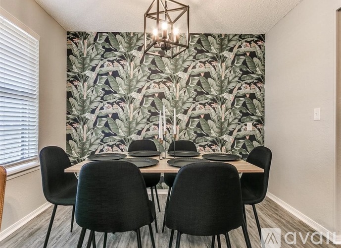 A dining room with a large floral wallpaper and a wooden table with six chairs.