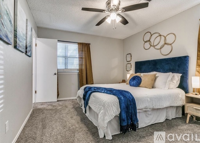 A bedroom with a white bed and a ceiling fan.