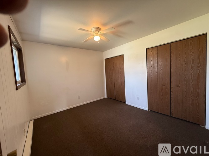 A room with a ceiling fan and two wooden doors.