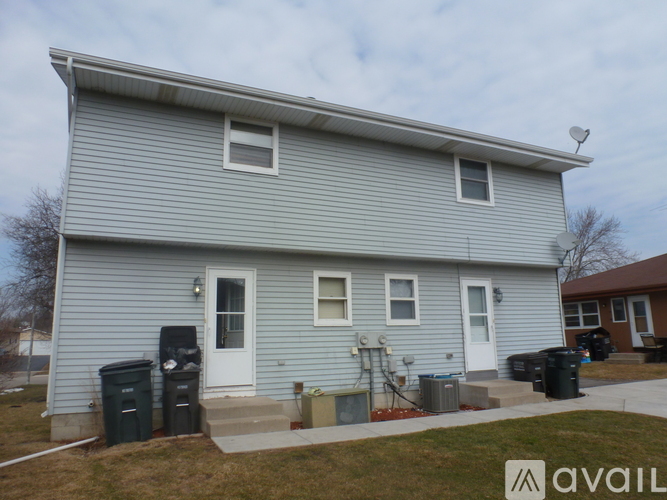 A house with a grey siding and a white door is shown.