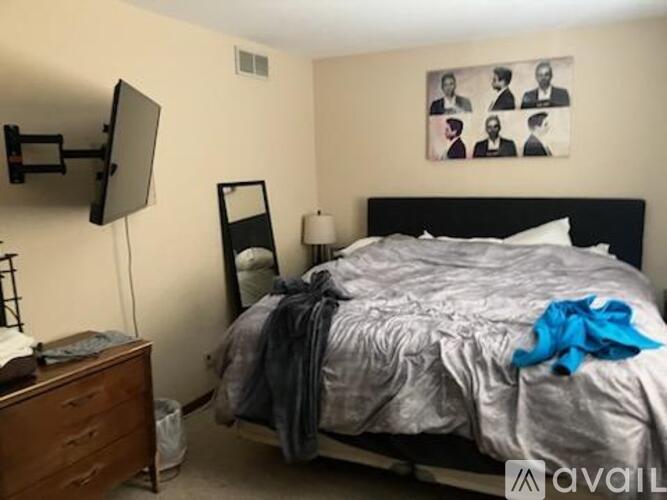 A bedroom with a bed, dresser, and a painting on the wall.