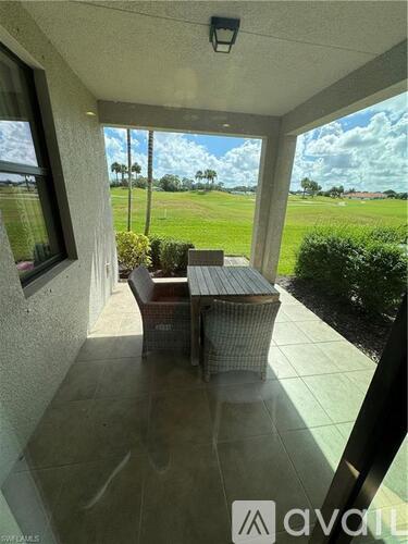 A patio with a table and chairs overlooks a grassy field.