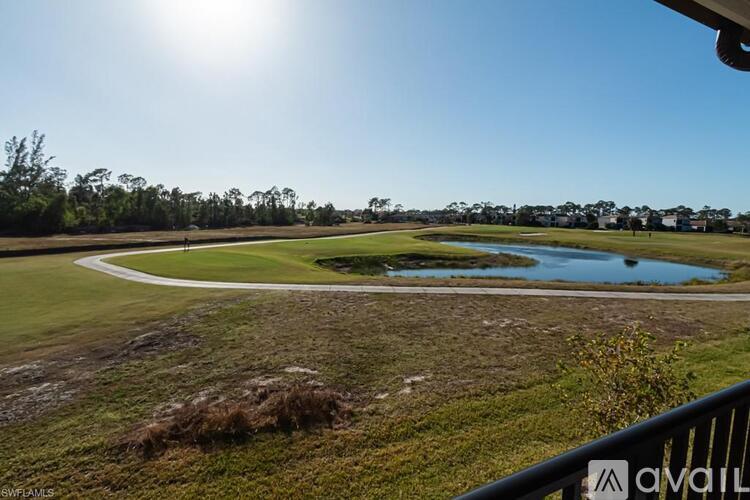 A golf course with a pond and trees in the distance.