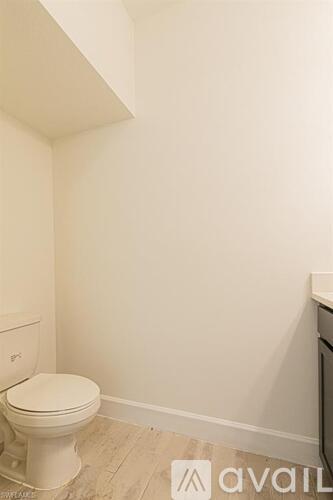 A white toilet in a small bathroom with a textured floor.