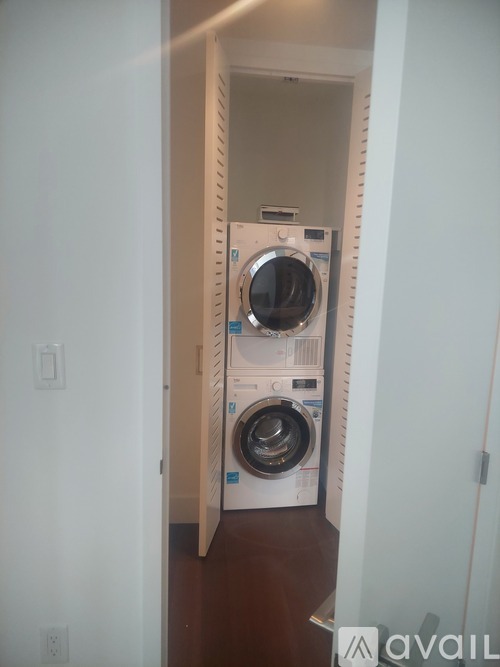 A white washer and dryer stacked on top of each other in a narrow hallway.