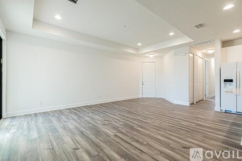 A spacious room with wooden flooring and white walls.