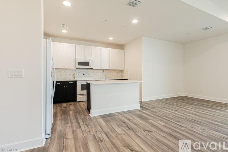 A kitchen with white cabinets and a black fridge is shown.