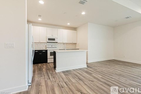 A kitchen with white cabinets and a black fridge is shown.