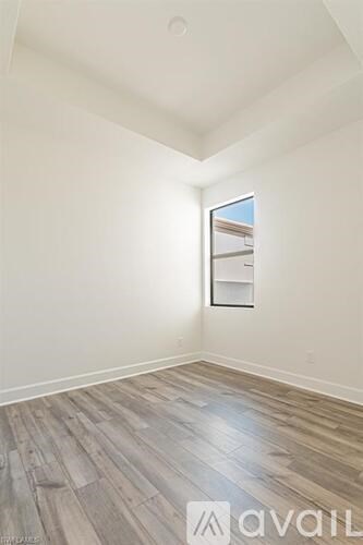 A room with wooden flooring and a window showing a building outside.