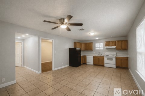 A kitchen with a black refrigerator and white appliances.