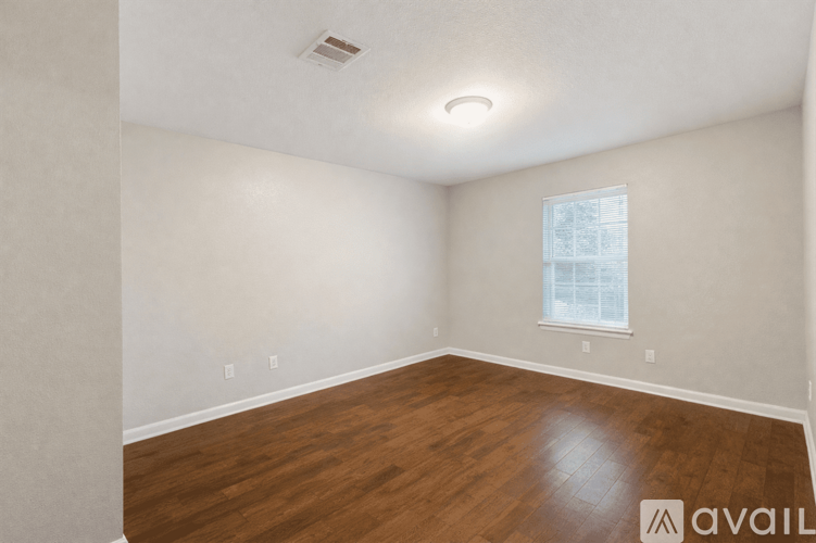 A room with wooden flooring and a window.