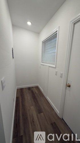 A hallway with wooden floors and white walls.