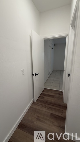 A hallway with wood floors and white walls.