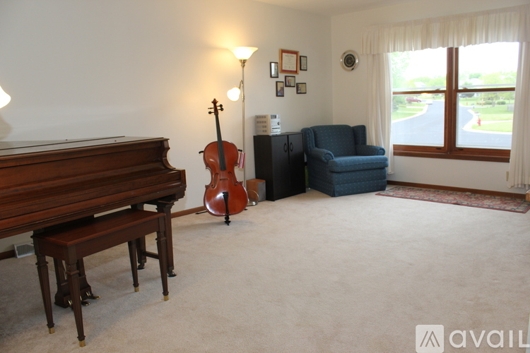 A room with a piano, a chair, and a guitar.