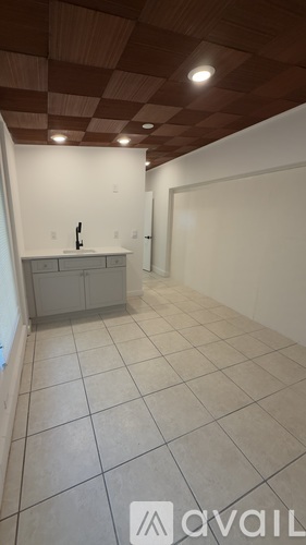 A kitchen with white cabinets and a checkered ceiling.