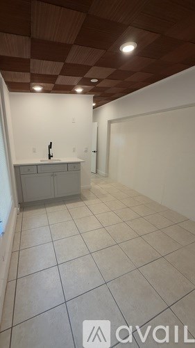A kitchen with white cabinets and a checkered ceiling.