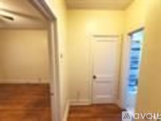 A hallway with a wooden floor and white walls.
