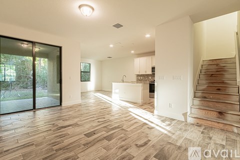 A modern kitchen with wooden floors and a staircase.